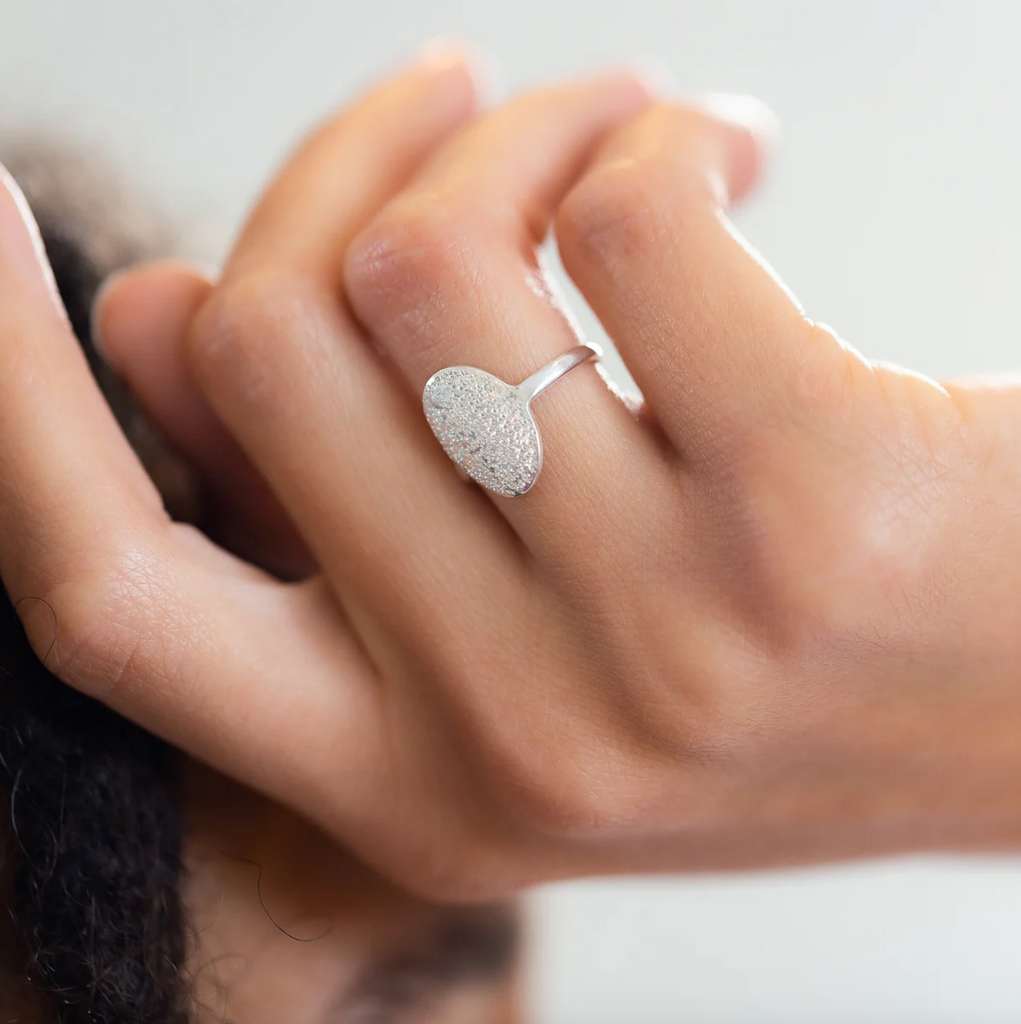 Silver ring on a person's finger with a blurred background