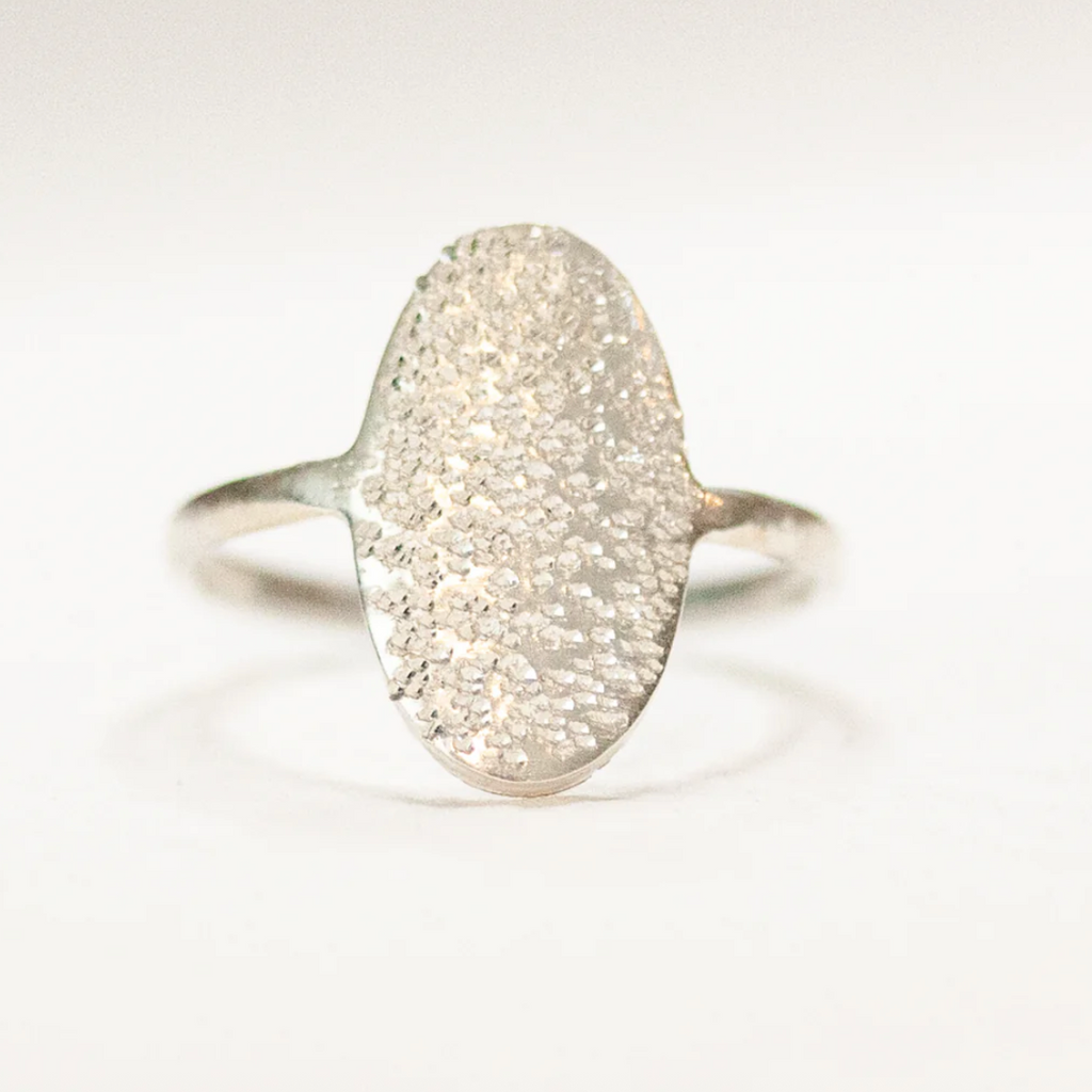 Silver ring with textured surface on a light gray background