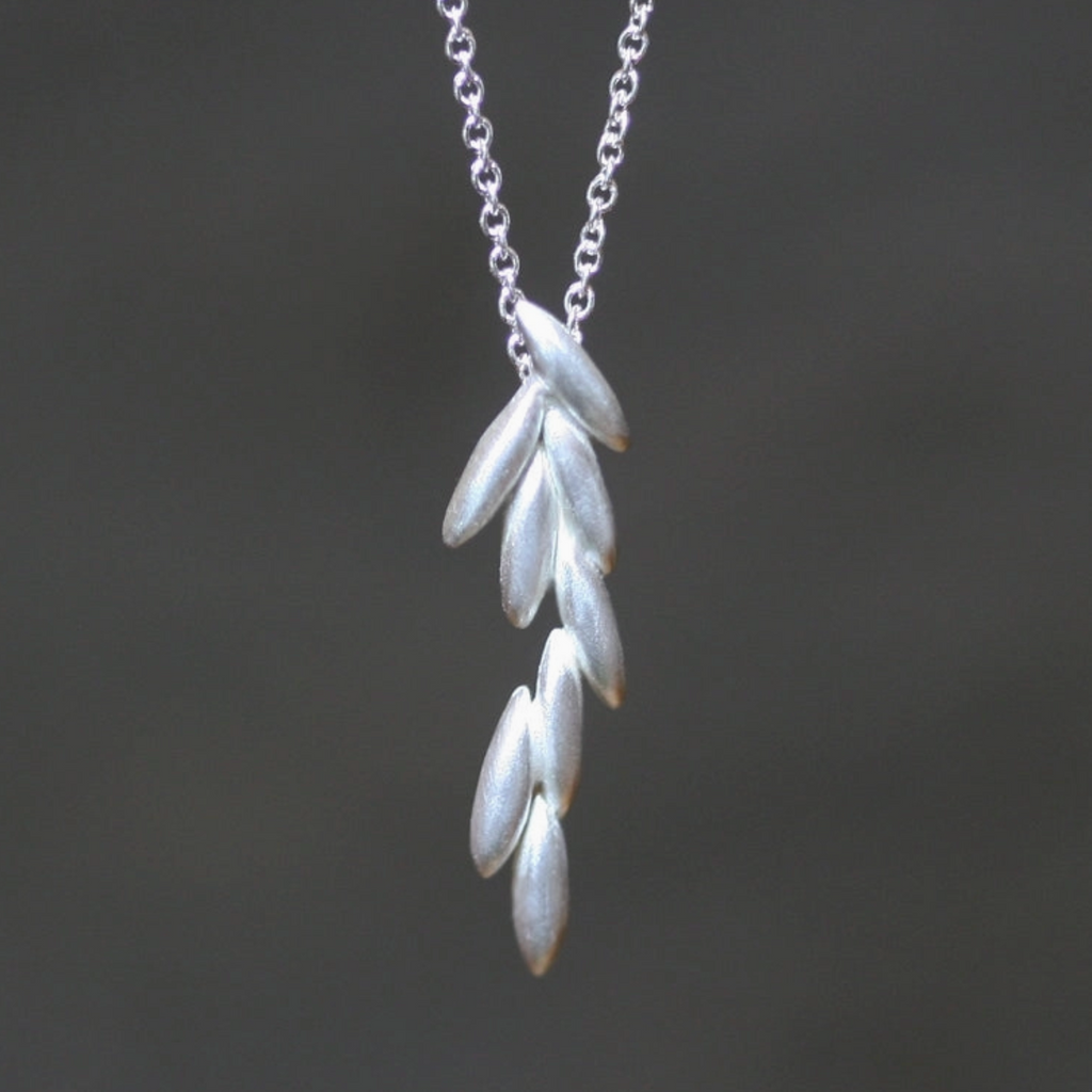 Silver leaf-shaped pendant on a chain against a dark background