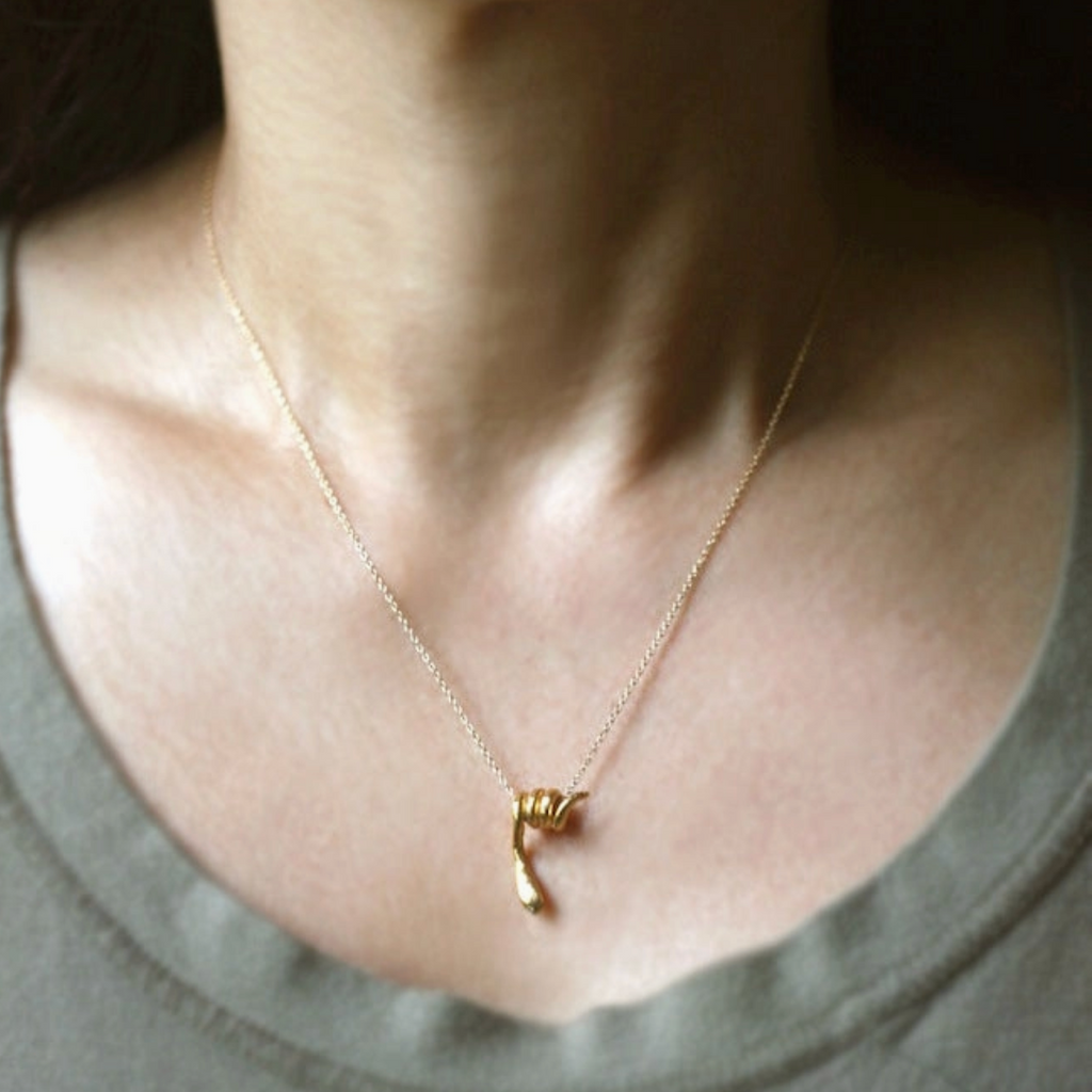 Gold necklace with a snake pendant worn by a person