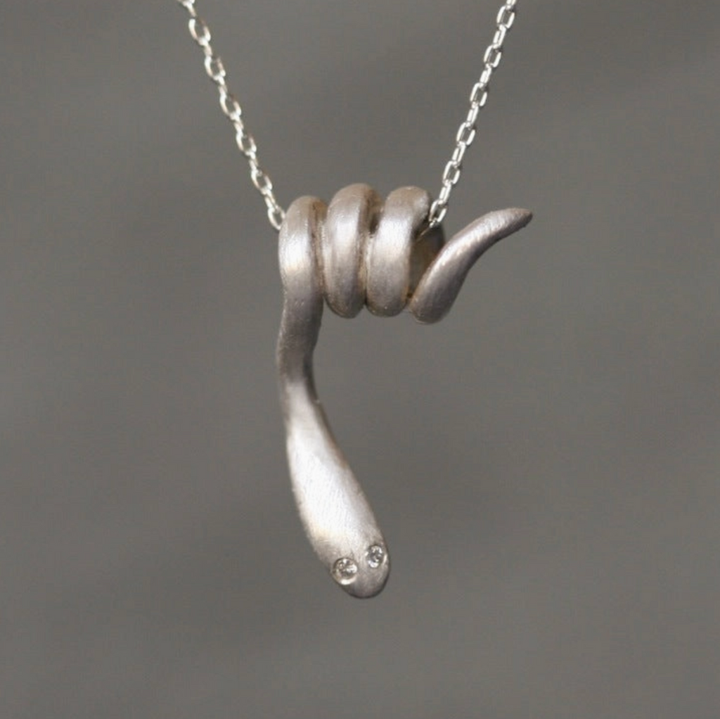 Silver necklace with a coiled snake pendant on a gray background